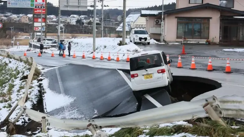 EPA Legenda da foto,Um carro ficou preso em uma estrada que desabou em Tohoku, no norte do Japão